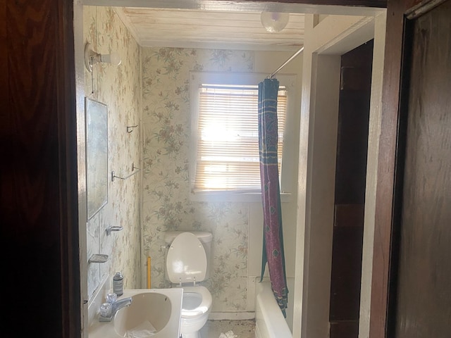 bathroom featuring shower / tub combo, a sink, toilet, and wallpapered walls