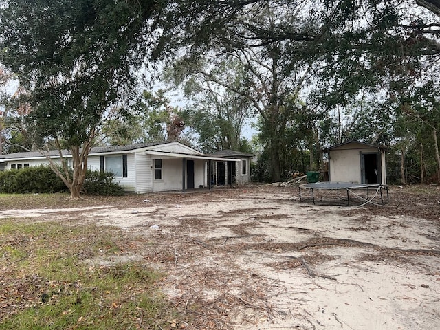 view of front of property with a trampoline and a storage unit