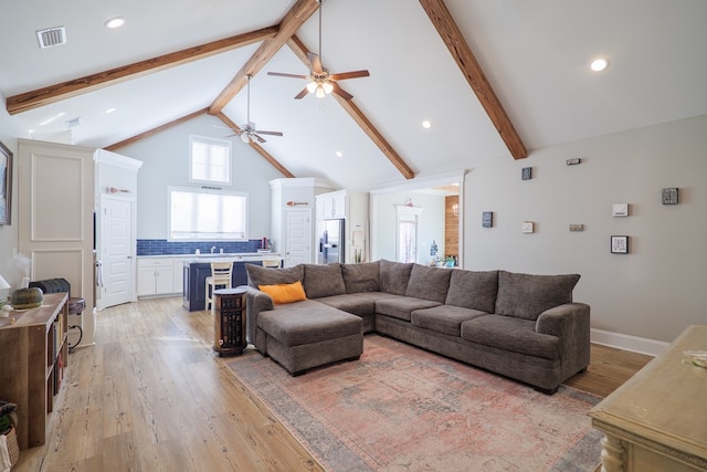 living room featuring sink, beam ceiling, high vaulted ceiling, and light wood-type flooring