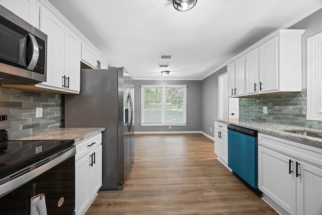 4848 Lori St, Valdosta, GA 31605 - kitchen featuring stainless steel appliances, crown molding, white cabinetry, light wood finished floors, and decorative backsplash