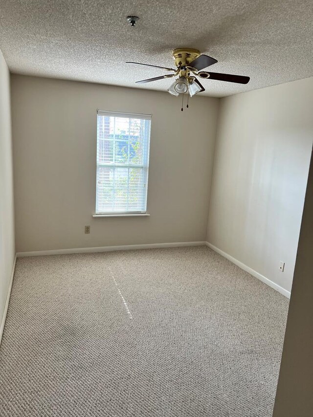 carpeted spare room with ceiling fan and a textured ceiling