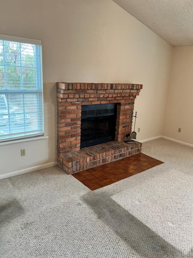 unfurnished living room with carpet floors, a textured ceiling, and a brick fireplace