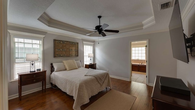 bedroom featuring ensuite bathroom, crown molding, a textured ceiling, dark hardwood / wood-style floors, and a raised ceiling