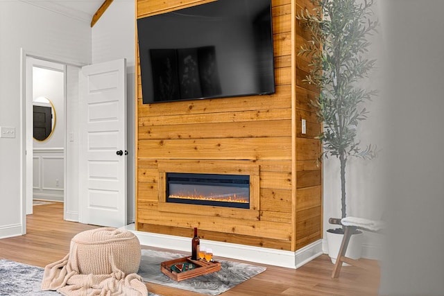 living room featuring crown molding, wood finished floors, and a glass covered fireplace