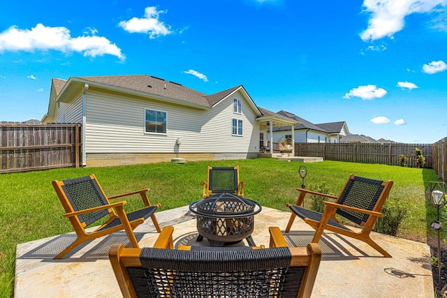 rear view of property featuring a fenced backyard, an outdoor fire pit, a patio area, and a lawn