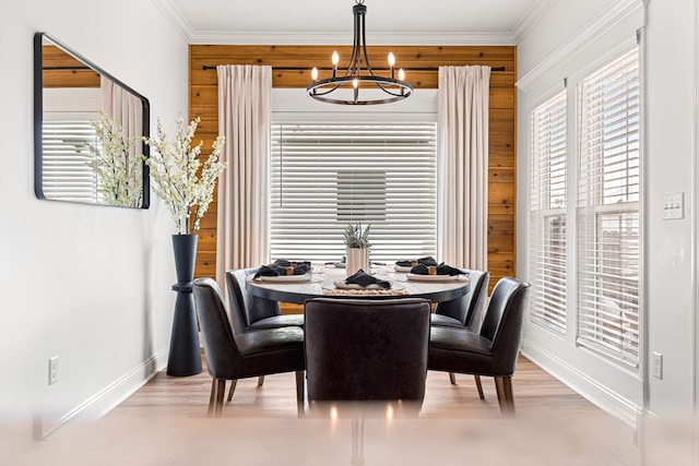 dining space featuring crown molding, light wood-style floors, a chandelier, and baseboards