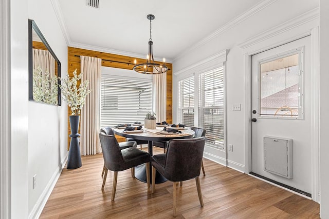 dining room featuring ornamental molding, light wood-type flooring, visible vents, a chandelier, and baseboards