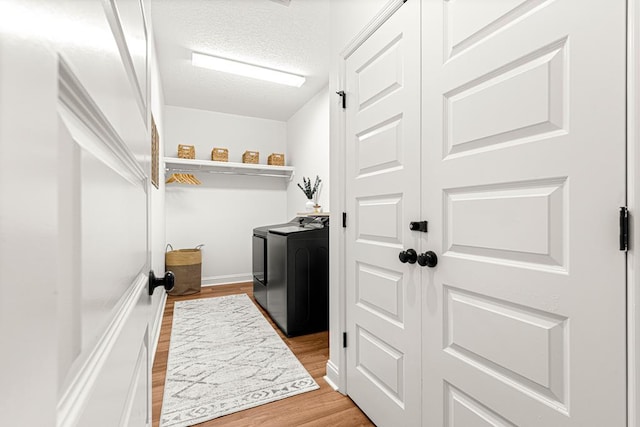 laundry room featuring washer and dryer, laundry area, a textured ceiling, and light wood-style flooring