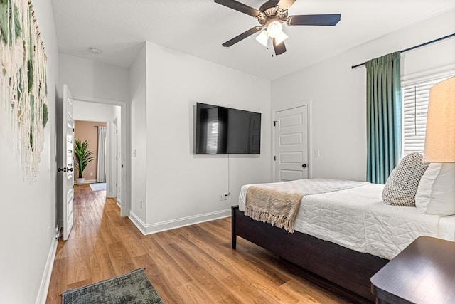 bedroom featuring light wood-type flooring, baseboards, and a ceiling fan