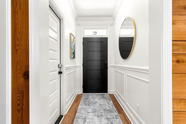 entryway featuring wainscoting, dark wood-style flooring, ornamental molding, and a decorative wall