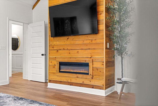 unfurnished living room with baseboards, a glass covered fireplace, and wood finished floors