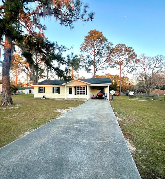 ranch-style home featuring driveway, a carport, and a front yard