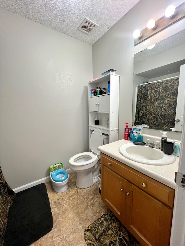 full bath featuring baseboards, visible vents, toilet, a textured ceiling, and vanity