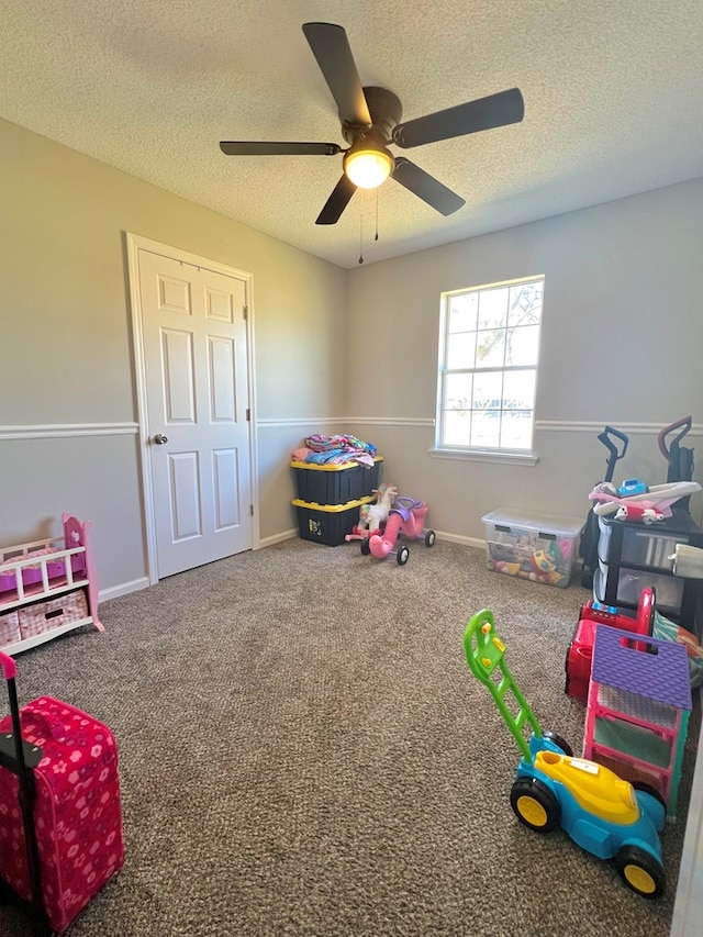 recreation room featuring a textured ceiling, carpet floors, and baseboards