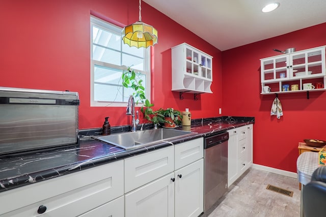 kitchen with sink, white cabinets, stainless steel dishwasher, and light hardwood / wood-style flooring