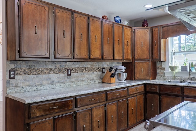 kitchen featuring light tile patterned floors, backsplash, light stone counters, and sink