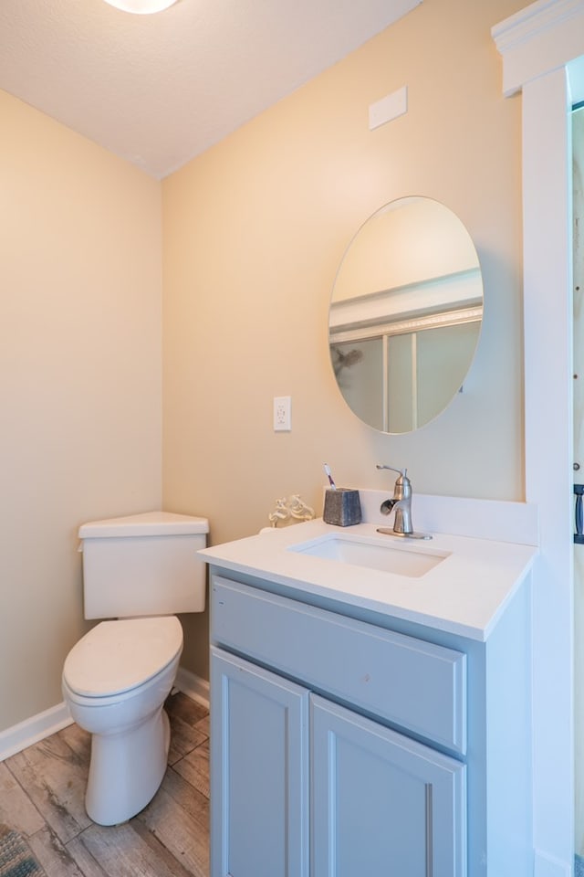 bathroom featuring wood-type flooring, vanity, and toilet