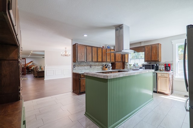 kitchen featuring decorative backsplash, island range hood, a kitchen island, and light hardwood / wood-style flooring