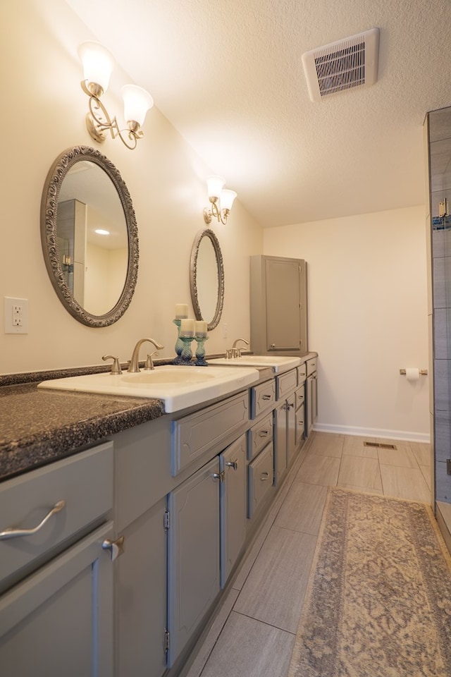 bathroom with vaulted ceiling, tile patterned flooring, vanity, and a textured ceiling