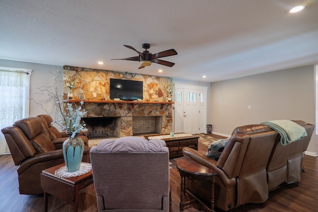 living room featuring ceiling fan, a fireplace, and dark wood-type flooring