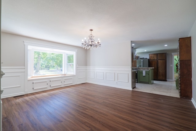 empty room with hardwood / wood-style floors, a notable chandelier, and a textured ceiling