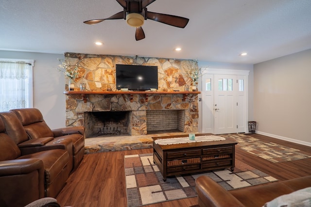 living room with a stone fireplace, hardwood / wood-style floors, and a healthy amount of sunlight