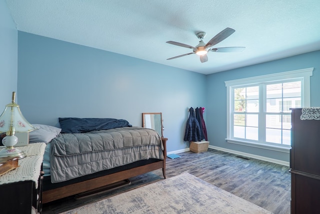 bedroom with hardwood / wood-style floors, ceiling fan, and a textured ceiling