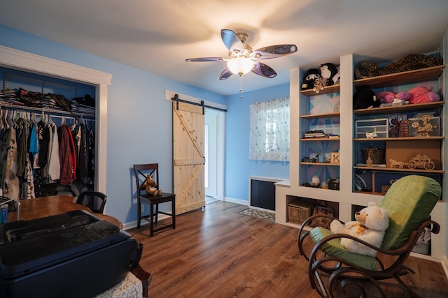 living area featuring dark hardwood / wood-style flooring, a barn door, and ceiling fan