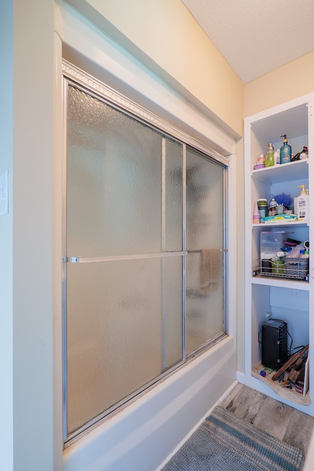 bathroom with hardwood / wood-style floors and enclosed tub / shower combo