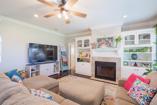 living area with a fireplace, ceiling fan, wood finished floors, and ornamental molding