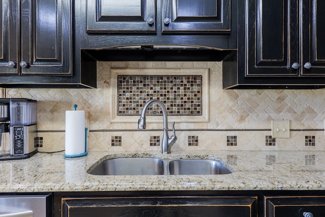 kitchen featuring light stone counters, backsplash, and a sink