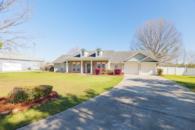 cape cod home featuring a front yard, an attached garage, driveway, and fence