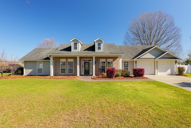 new england style home with driveway, roof with shingles, a front yard, an attached garage, and brick siding