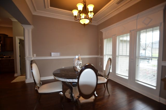 dining area with dark hardwood / wood-style floors, ornate columns, a wealth of natural light, and a chandelier