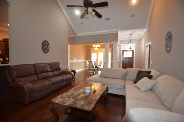 living room featuring decorative columns, ornamental molding, ceiling fan with notable chandelier, dark wood-type flooring, and high vaulted ceiling