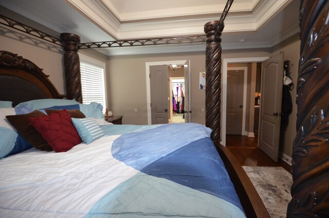 bedroom featuring a raised ceiling, crown molding, and dark wood-type flooring