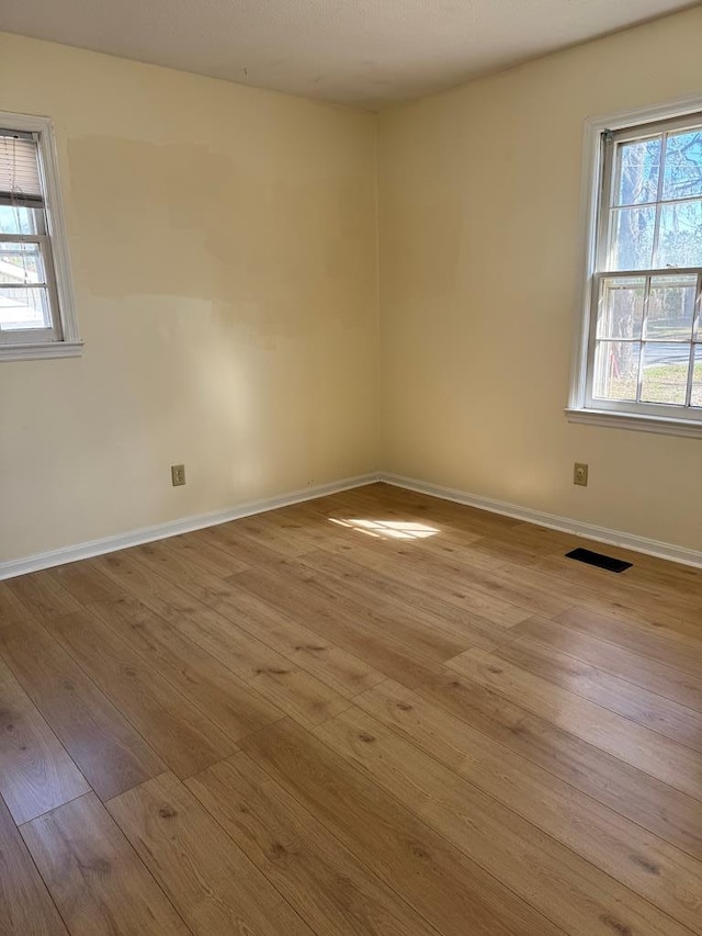 unfurnished room with visible vents, light wood-type flooring, and baseboards