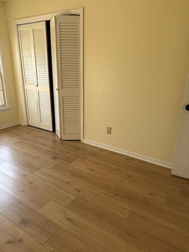 unfurnished bedroom with a closet, baseboards, and wood finished floors