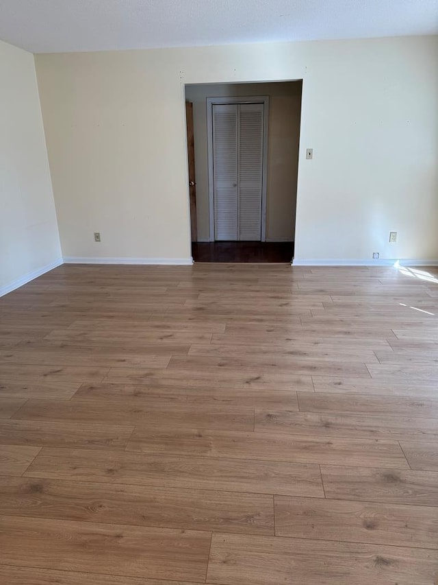 spare room featuring baseboards and light wood finished floors