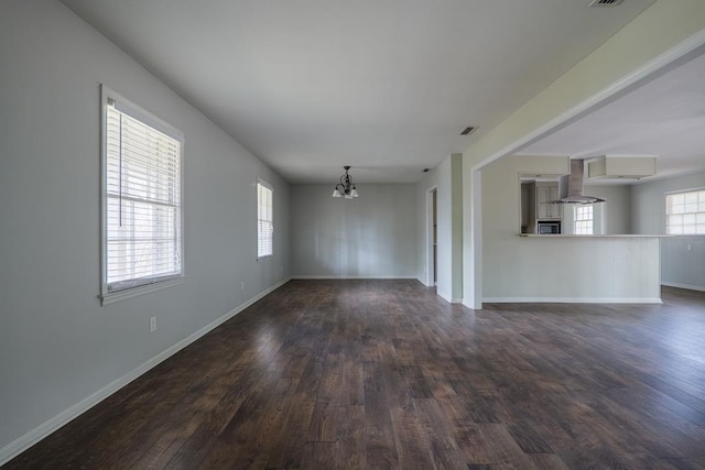 2205 Briarcliff Dr, Valdosta, GA 31602 - unfurnished living room featuring an inviting chandelier, dark wood-style floors, and baseboards