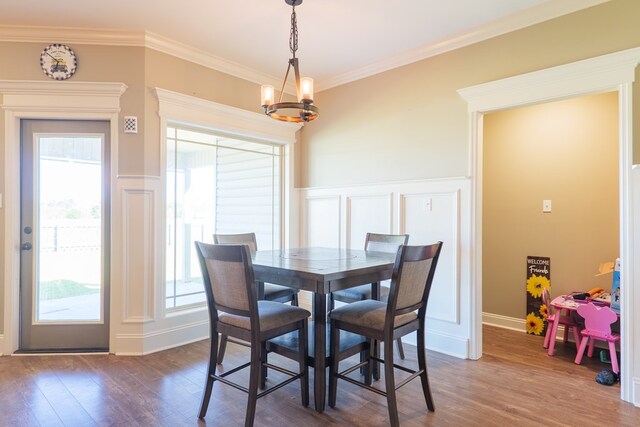 3908 Crusader Ct, Valdosta, GA 31605 - dining room with a notable chandelier, a decorative wall, ornamental molding, and dark wood-style flooring
