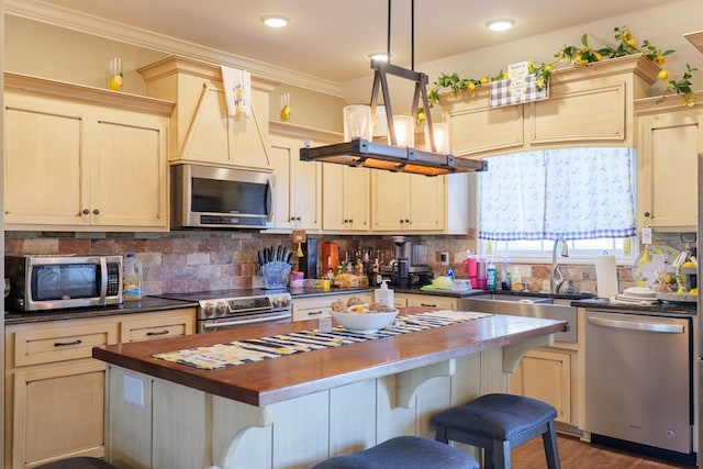 3908 Crusader Ct, Valdosta, GA 31605 - kitchen with ornamental molding, stainless steel appliances, a kitchen island, a sink, and backsplash