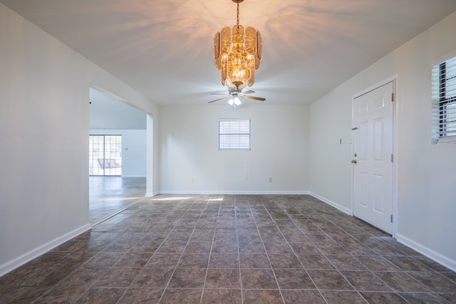 empty room with ceiling fan with notable chandelier and a healthy amount of sunlight