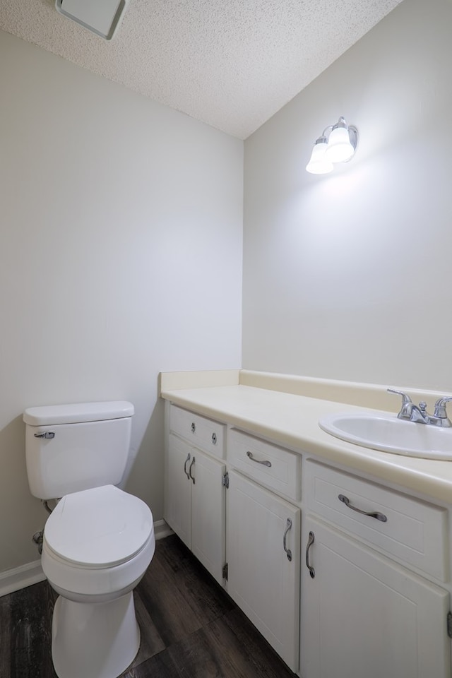 bathroom featuring vanity, toilet, wood-type flooring, and a textured ceiling