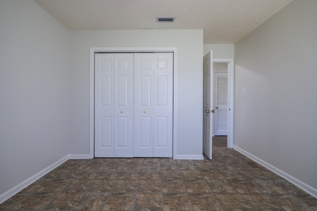 unfurnished bedroom featuring a textured ceiling and a closet