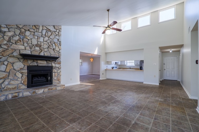 unfurnished living room featuring ceiling fan, a stone fireplace, and high vaulted ceiling