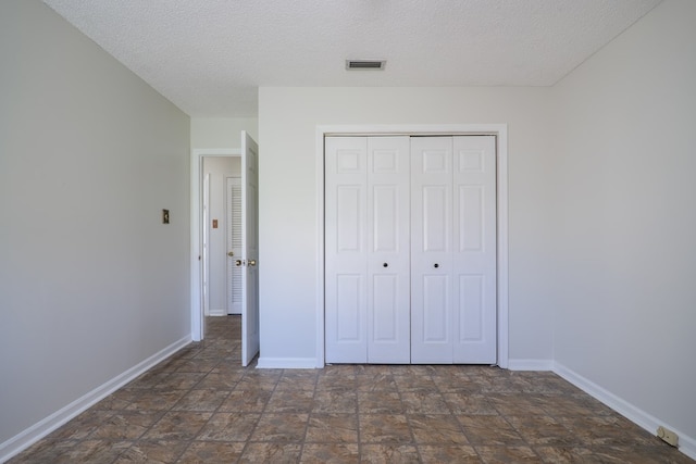 unfurnished bedroom with a textured ceiling and a closet