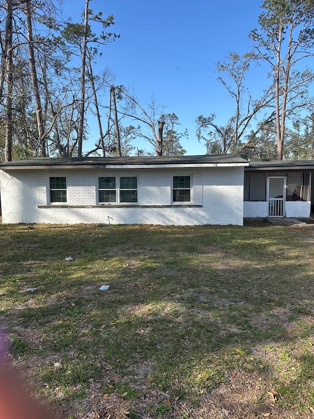 back of house with brick siding, a yard, and a sunroom