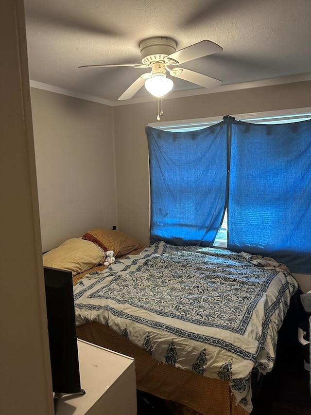 bedroom with a textured ceiling, a ceiling fan, and crown molding