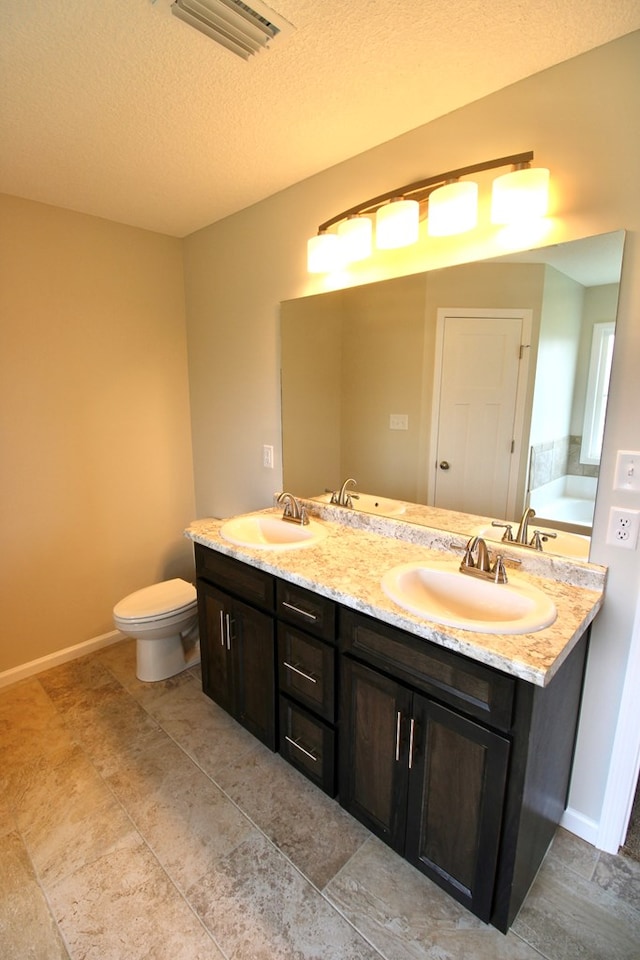 bathroom with toilet, double vanity, a sink, and visible vents